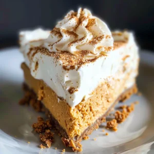 Close-up of a slice of no-bake pumpkin cheesecake topped with whipped cream and a sprinkle of cinnamon.