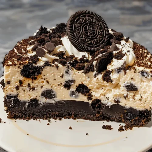A delicious slice and whole Oreo cheesecake, topped with whipped cream and Oreo cookie crumbs.